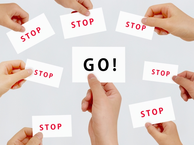 GOとSTOPがかかれた紙を持つ手元